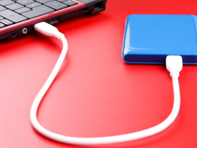 A blue external hard drive connected to a working laptop